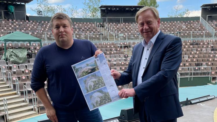 Geschäftsführer Falk Herzog präsentiert Ingo Gädechens einen Plan der neuen Tribüne
